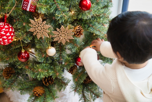 子供がクリスマスツリーに飾り付けをしている様子