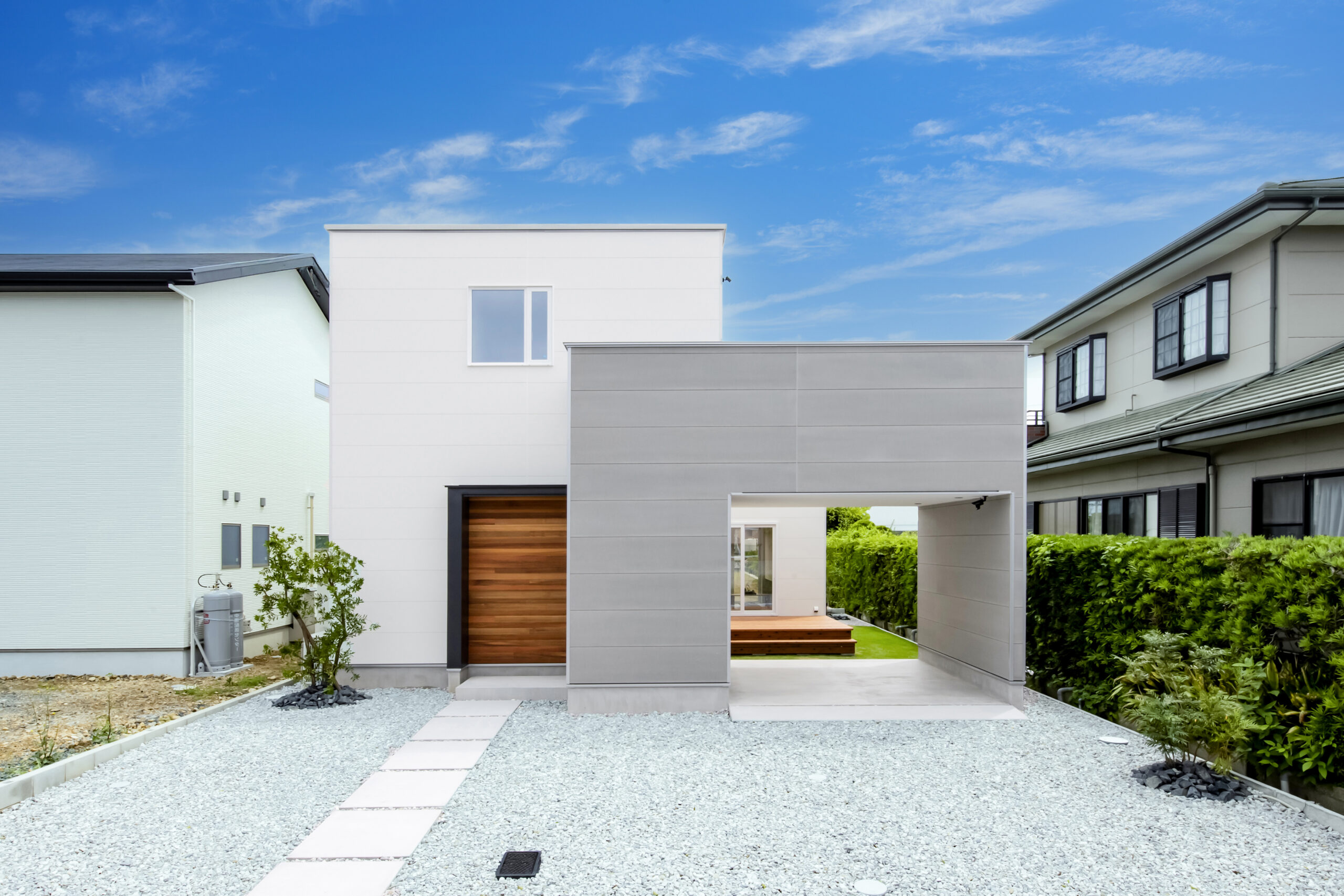 青空を背景に佇む白いとグレーのコントラストが美しい家