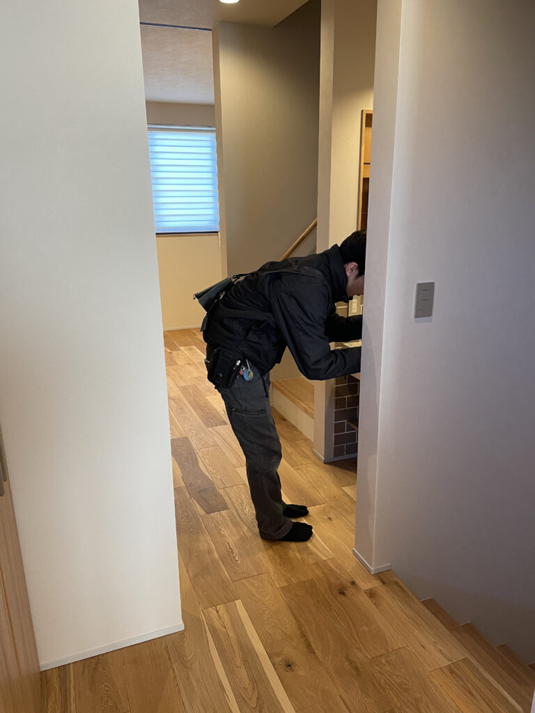 新築住宅の内覧・検査風景。廊下から洗面スペースへと続く木目調フローリングの施工状態を確認する。