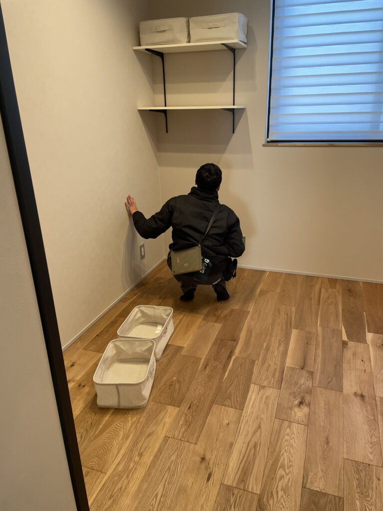 クローゼットや収納スペースの最終検査。可動棚と壁面の仕上がりを手で触れて確認する様子。
